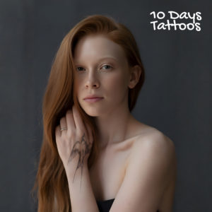 Jeune femme avec un tatouage temporaire d’hirondelle sur la main gauche