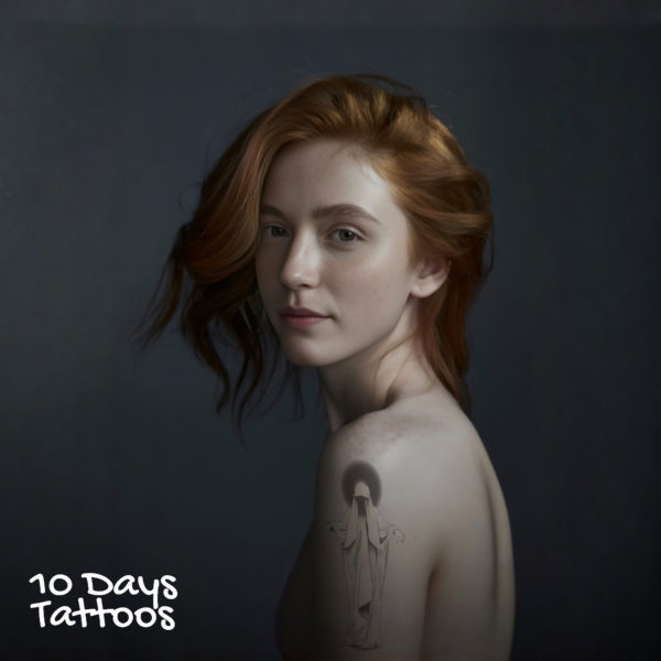 Jeune femme avec tatouage silhouette à capuche en style blackwork sur l’épaule gauche