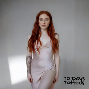 Jeune femme avec tatouage semi-permanent visage de femme et œil qui voit tout sur l’avant-bras droit