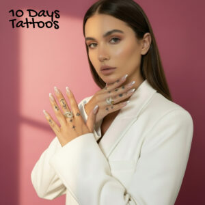 Mini tatouages temporaires noirs étoiles lunes et symboles mystiques sur doigts d’une femme en blazer blanc fond rose 10 Days Tattoos