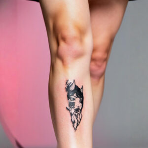 Gros plan cuisse femme portant le tatouage temporaire Aku, visage oni féminin kanji 悪 style gravure japonaise mokuhanga 14 × 6 cm, encre noire mat, fond rose corail